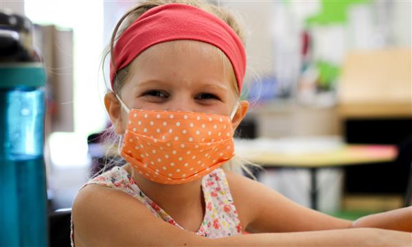 girl smiles while wearing mask